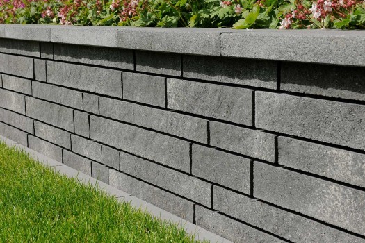 Linaro Mauer Anthrazit-grau gemasert changierend mit überstehender Abdeckplatte in Kombination mit Basalt Anthrazit 8-10 cm und Belpasso Grigio brillant.